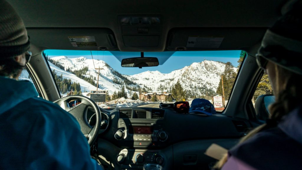 Two people in a car, looking out towards a snowy mountain range